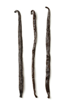 Dried Bourbon vanilla pods, vanilla beans from above. Three whole, dark brown and ripe fruits of Vanilla planifolia, a spice with distinctive flavor, used in baking. Top view, on white background.
