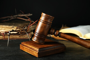 Wooden judge gavel and crown of thorns on black table, closeup