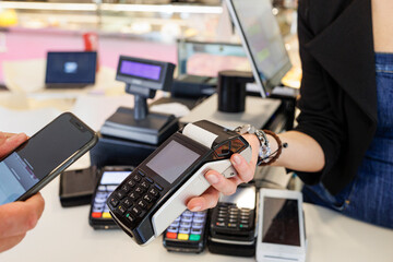 Dettaglio del pagamento con carta di credito con uno smartphone verso il pos di tenuto dalla mano...