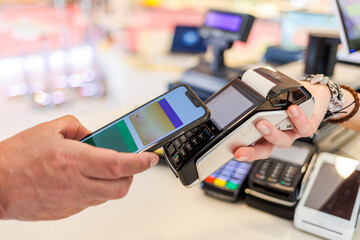 Dettaglio del pagamento con carta di credito con uno smartphone verso il pos di tenuto dalla mano...