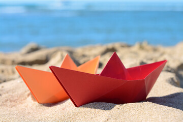 Two paper boats near sea on sunny day, closeup
