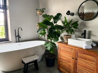 Charming cozy bathroom view. Bath tube by the window. Taking bath at home or in a hotel. Charming...