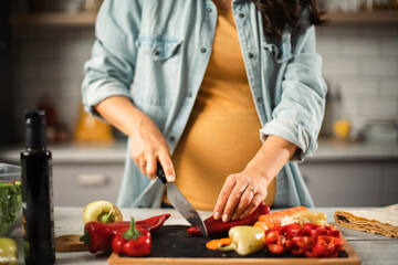 Obraz na płótnie Canvas Young woman in kitchen. Beautiful pregnant woman making salad.