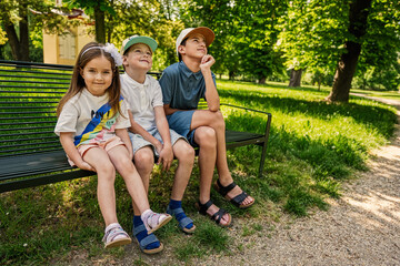 Three kids sitting in bench at park. Two brothers and sister.