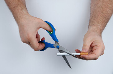Quit smoking: hands with scissors cutting a cigarette