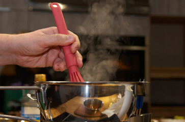 Cooking process: whisking sauce in a saucepan with rising steam