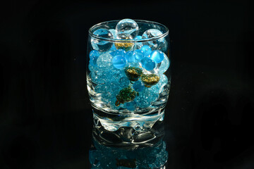 blue beads balls in glass on black mirror background