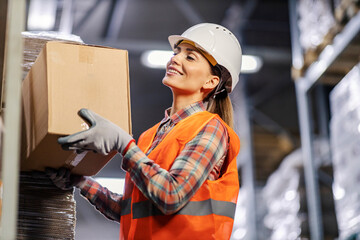 A female wholesale worker is arranging boxes on shelves in facility.