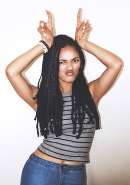 Portrait, hand gesture and horns with a black woman posing in studio on a gray background for quirky fun. Face, fashion and beauty with an attractive young female making a devil horn sign with hands