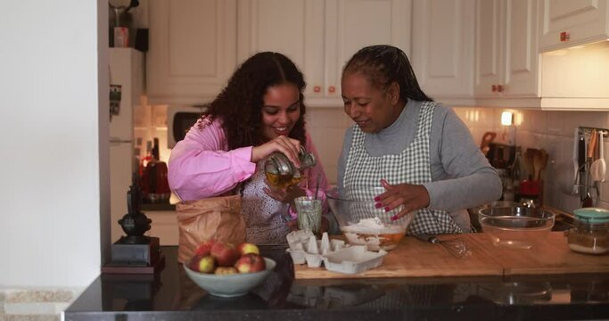 African mother and daughter preparing fruit cake at home - Family and cooking concept