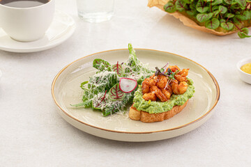 Fototapeta na wymiar Portion of avocado toast with grilled shrimp and salad