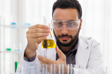 Close-up of laboratory researcher holding oil glass bottle with yellow petroleum  liquid wearing a...
