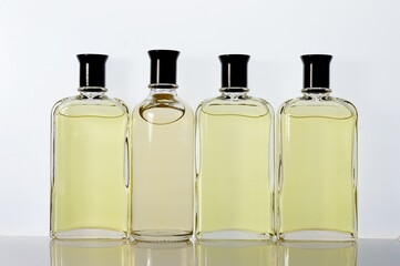 Transparent, glass jars with perfume liquid stand on a white surface