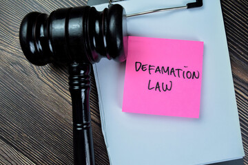 Concept of Defamation Law write on sticky notes with gavel isolated on Wooden Table.