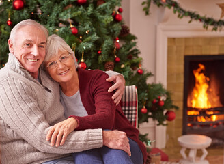 Love, portrait and senior couple at a christmas party or celebration relaxing in the living room of their home. Happy, smile and elderly man and woman embracing at a festive xmas event at a house.
