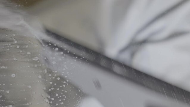 Vertical video of man Washing sharpie marker from window with cleaning spray