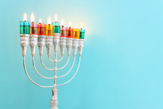 Image of jewish holiday Hanukkah with menorah (traditional candelabra) and colorful oil candles
