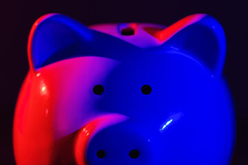 Close up Piggy bank on a dark background with red-blue backlight. Banking concept. Bright neon lights