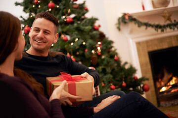 Obraz na płótnie Canvas Christmas, gift and happy family celebration of a man with a present at a holiday party. Couple with love and care on the holidays together with gifting box feeling happiness with a smile at home