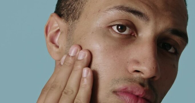 Positive man applying face cream. Closeup of male model with fresh skin applying