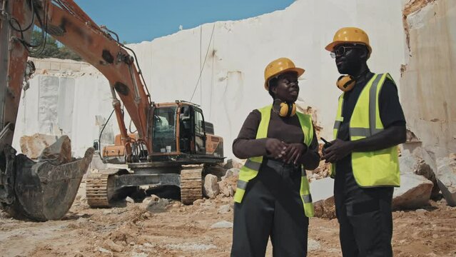 African American man and woman working in marble quarry discussing stones extraction problem