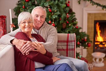 Christmas, senior couple and on couch together for happiness, festive season and relax at home. Xmas, love and elderly man with mature woman, happy or smile for bonding, content and on sofa in lounge