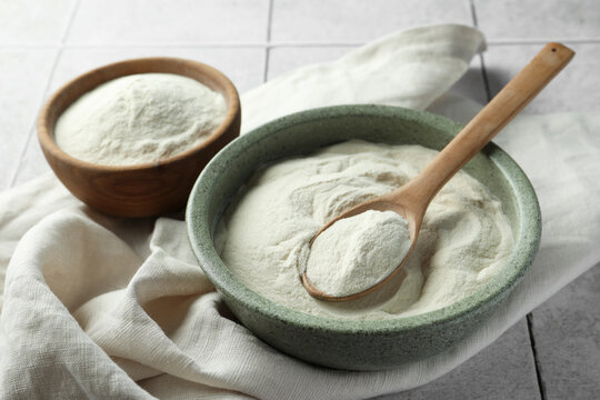 Bowls and spoon of agar-agar powder on tiled table, closeup