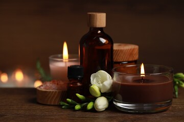 Fototapeta na wymiar Beautiful spa composition with burning candles, different care products and flowers on wooden table