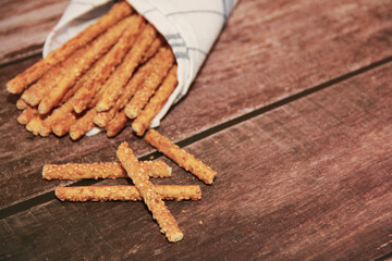 dry sesame bread sticks with small seeds for dietary nutrition, on a wooden background
