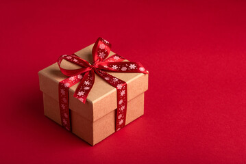 Christmas gift box with red bow on red background.