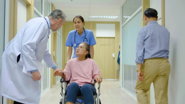 Nurse push Asian senior adult patient wheelchair in hospital hallway, Mature doctor showing and discussing medical report and examines the knee senior disabled with care, Medical healthcare job