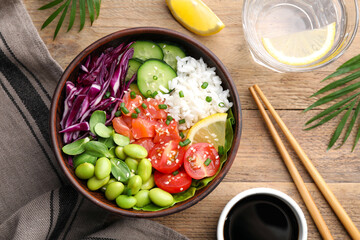 Poke bowl with salmon, edamame beans and vegetables on wooden table, flat lay