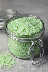 Jar with green sea salt on light grey table, closeup