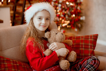 happy little girl holds teddy bear near the Christmas tree at home for Christmas


