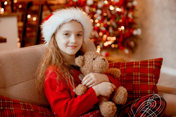 happy little girl holds teddy bear near the Christmas tree at home for Christmas

