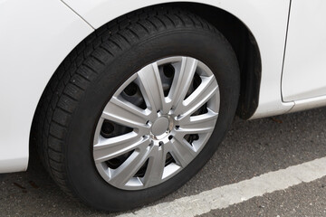 Fototapeta na wymiar White car with a new winter tire.
