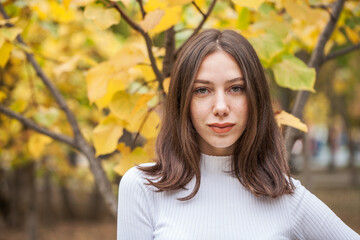 Young beautiful brown-haired girl in autumn park