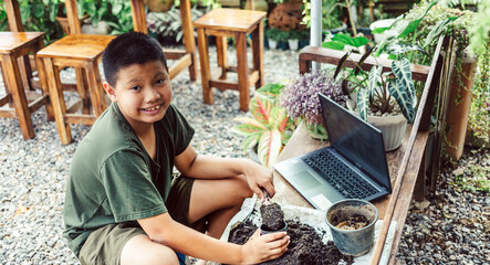 Boy learns to grow flowers in pots through online teaching. shoveling soil into pots to prepare plants for planting leisure activities concept