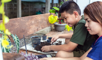 Fototapeta premium Portrait of a mother and son special moment. Gardening discovering and teaching learns to grow flowers in pots through online teaching leisure activity concept