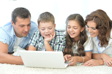 parents with children with laptops are lying on the back