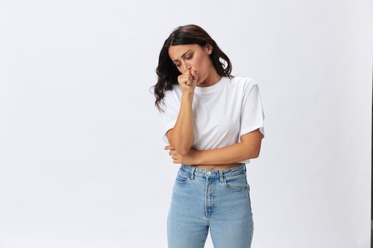 Woman sore throat and inflammation of the ligaments with a cold, a woman in a white t-shirt and jeans on a white background, copy space