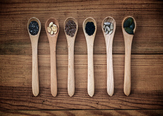 Set of organic seeds in spoons on wooden background, healthy natural food and nutrition concept