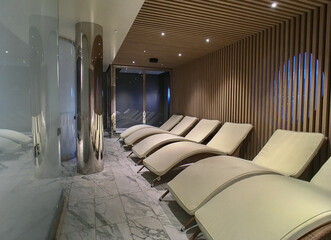 Warm stone loungers for relaxation inside thermal suite room area in spa wellness section of modern...
