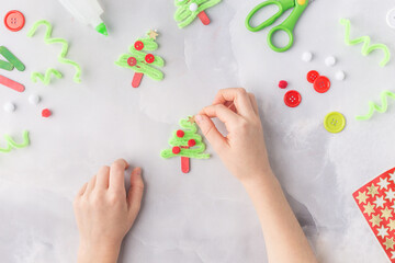 The child makes a greeting card Christmas paper collage. Made with his own hands. Children's art project craft for kids. Craft for children. Top view