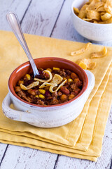 a view into a bowl of chili con carne topped with corn chips.