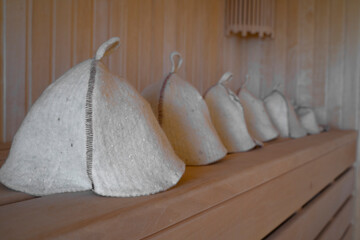 Close-up woolen hats for baths and saunas lie on a wooden bench in the steam room. Sauna hats.