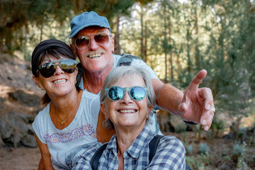 Group of happy smiling old people enjoying a mountain hike in the forest appreciating leisure and...