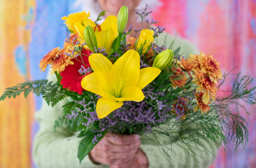 Senior caucasian woman holding a bouquet of flowers isolated on colorful background. Valentine's Day Women's Day birthday holiday party.