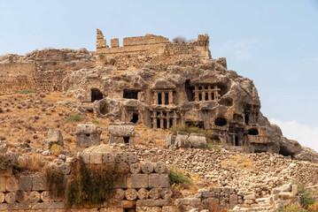 Fototapeta na wymiar Turkey. Fethiye. Rock burials. Rock-cut tombs. Turkish Mediterranean. At base of rock are ruins of destroyed ancient columns. Selective focus.