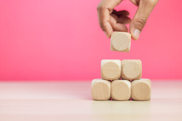 Hand holding stack wooden block arranging step pink background, stacking wood grow. education, box,...